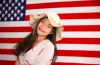 portrait_smiling_young_woman_standing_against_american_flag_1b1e14972f.jpg